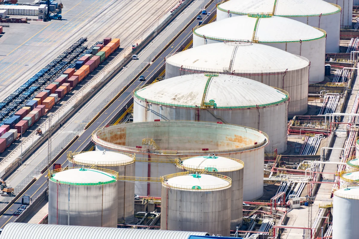 Aerial view of oil storage tanks, pipe racks and an adjacent rail yard