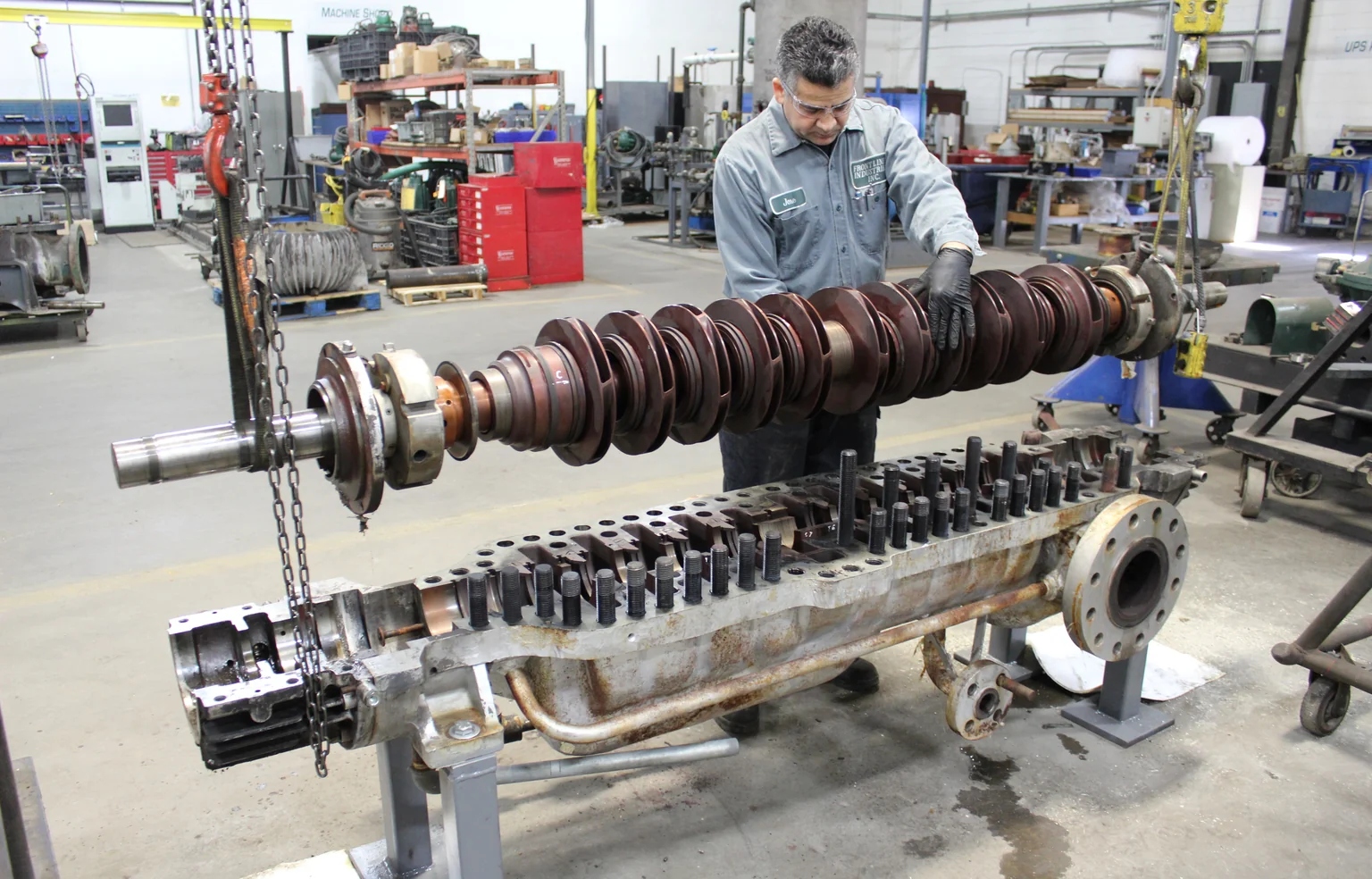 Technician handling a pump rotor above an open casing