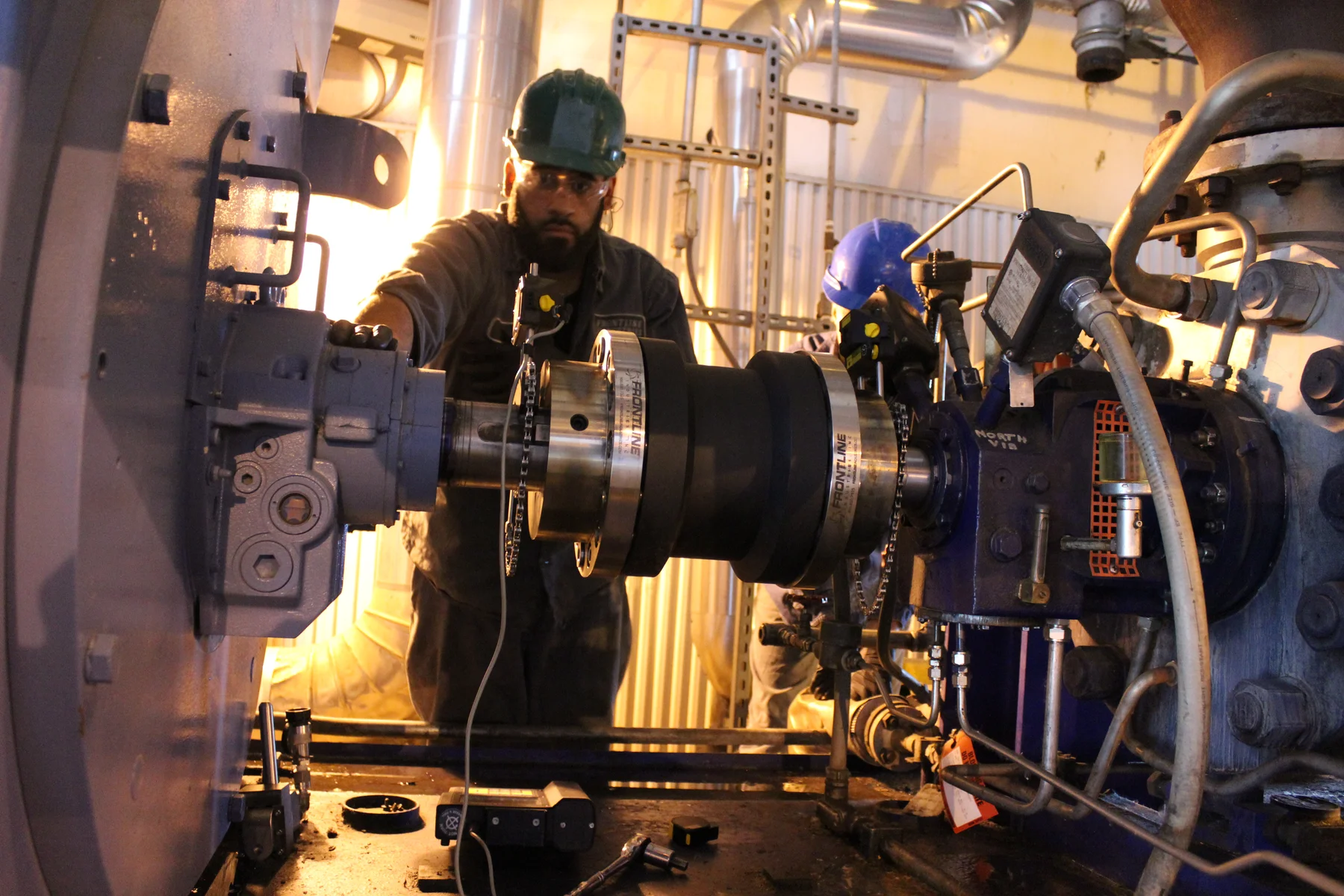 Technician using alignment equipment beside a rotating assembly